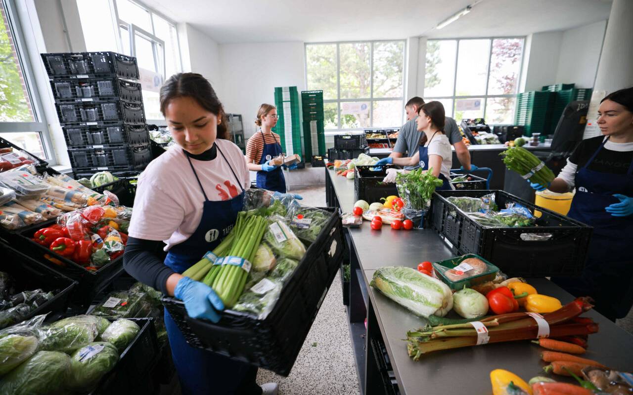 Freiwillige Helfer und Helferinnen sortieren und geben Lebensmittel bei der Tafel an Bedürftige aus.