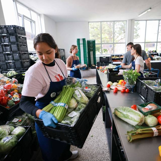 Freiwillige Helfer und Helferinnen sortieren und geben Lebensmittel bei der Tafel an Bedürftige aus.