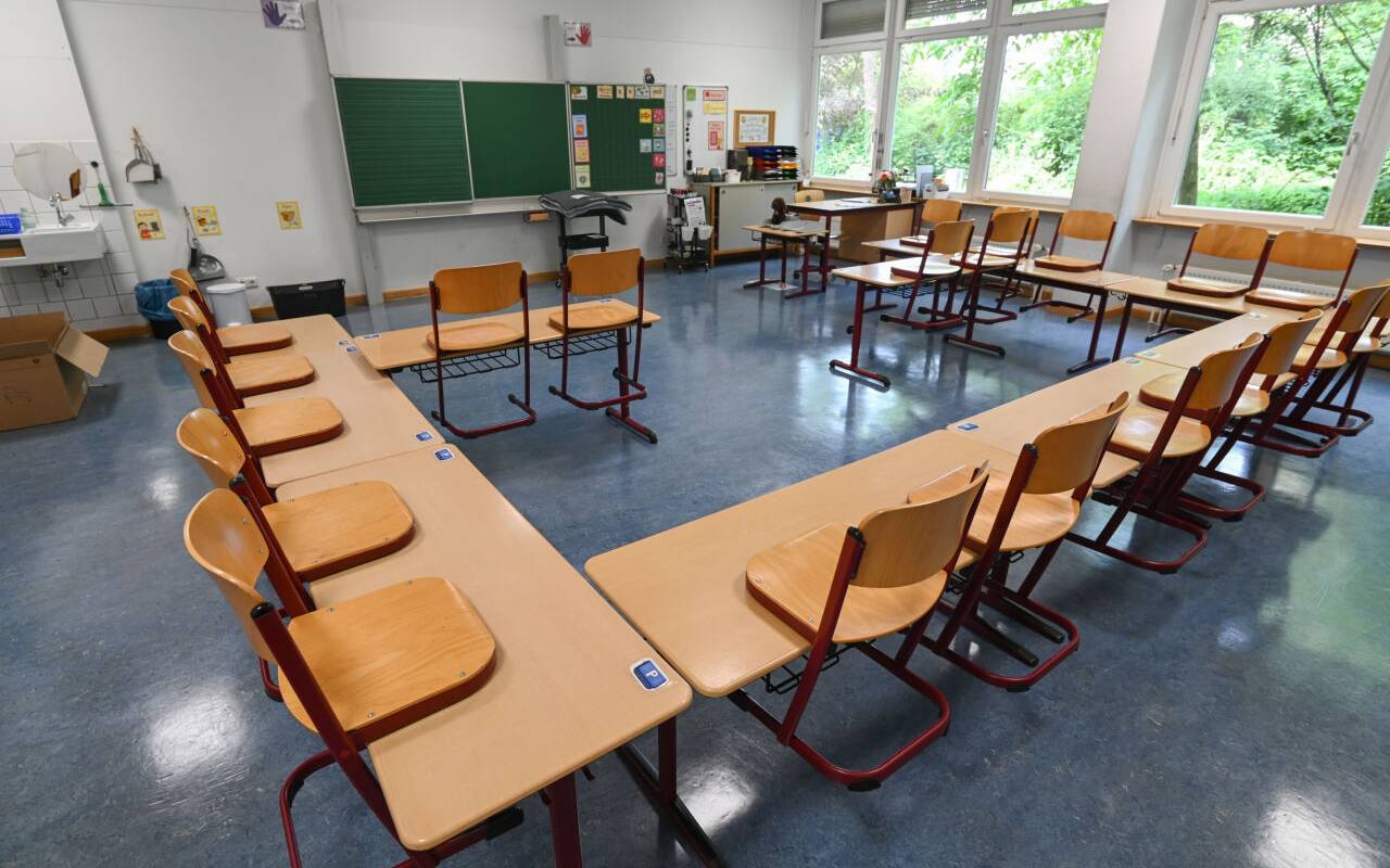 Stühle stehen in einem leeren Klassenzimmer auf den Tischen.
