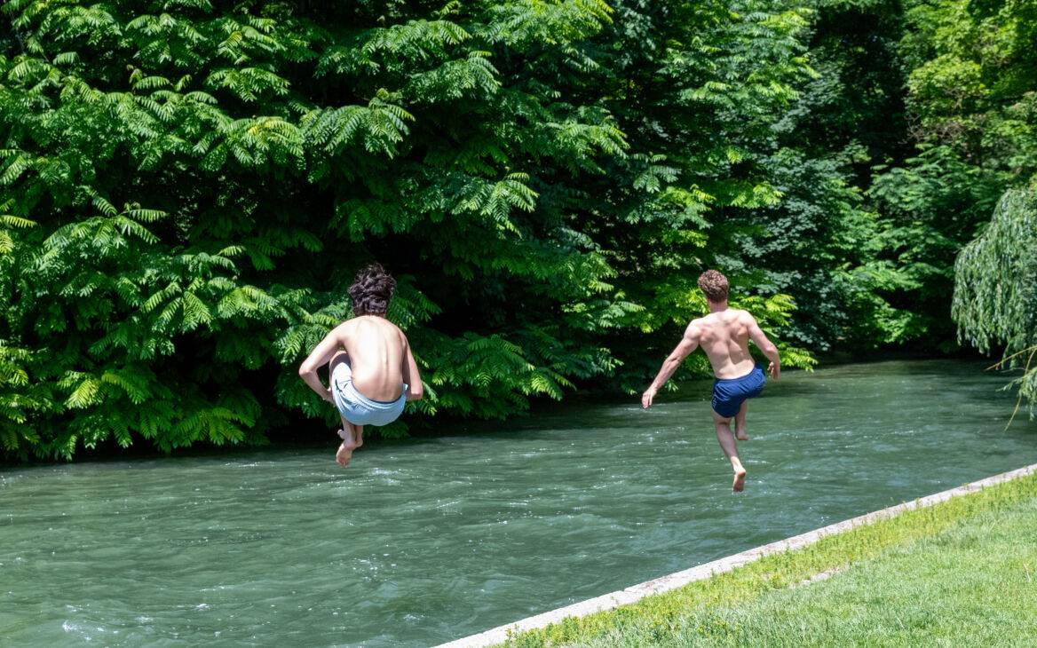 Zwei Jugendliche springen bei heißen Temperaturen zur Abkühlung in einen Fluss.