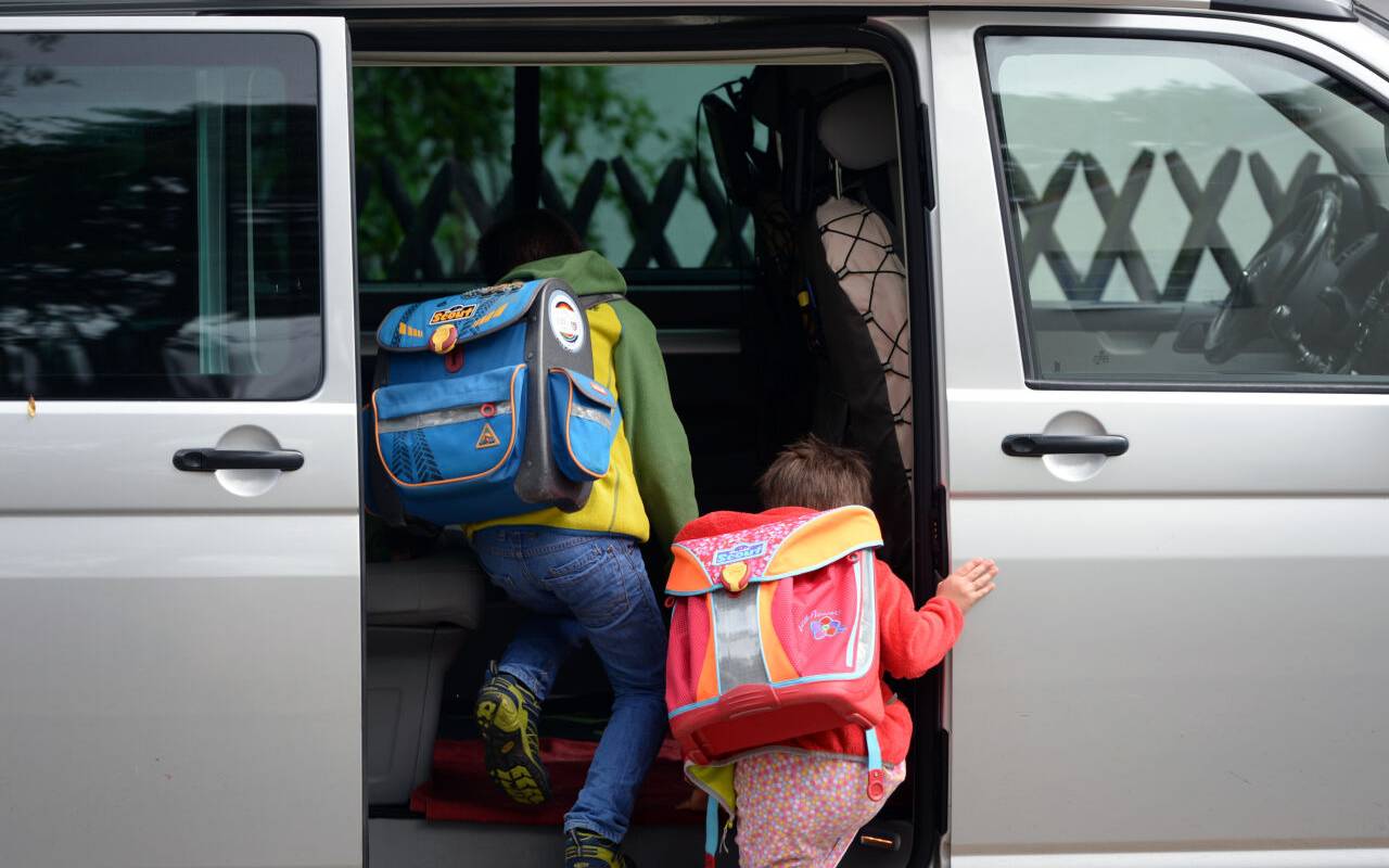 Vor einer Schule steigen Kinder ein privates Fahrzeug