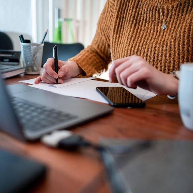 Frau sitzt mit einem Laptop am Tisch