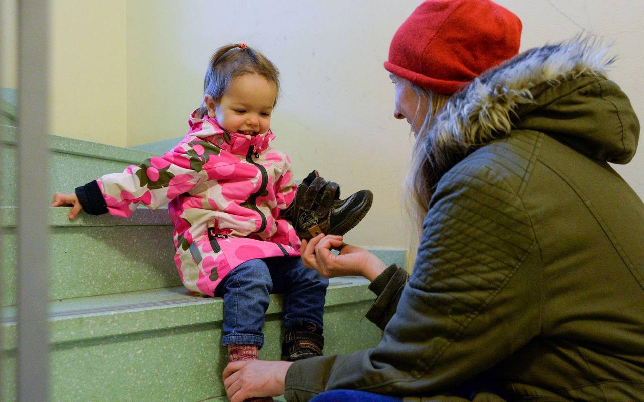 Eine Mutter hilft einem Kleinkind die Schuhe anzuziehen