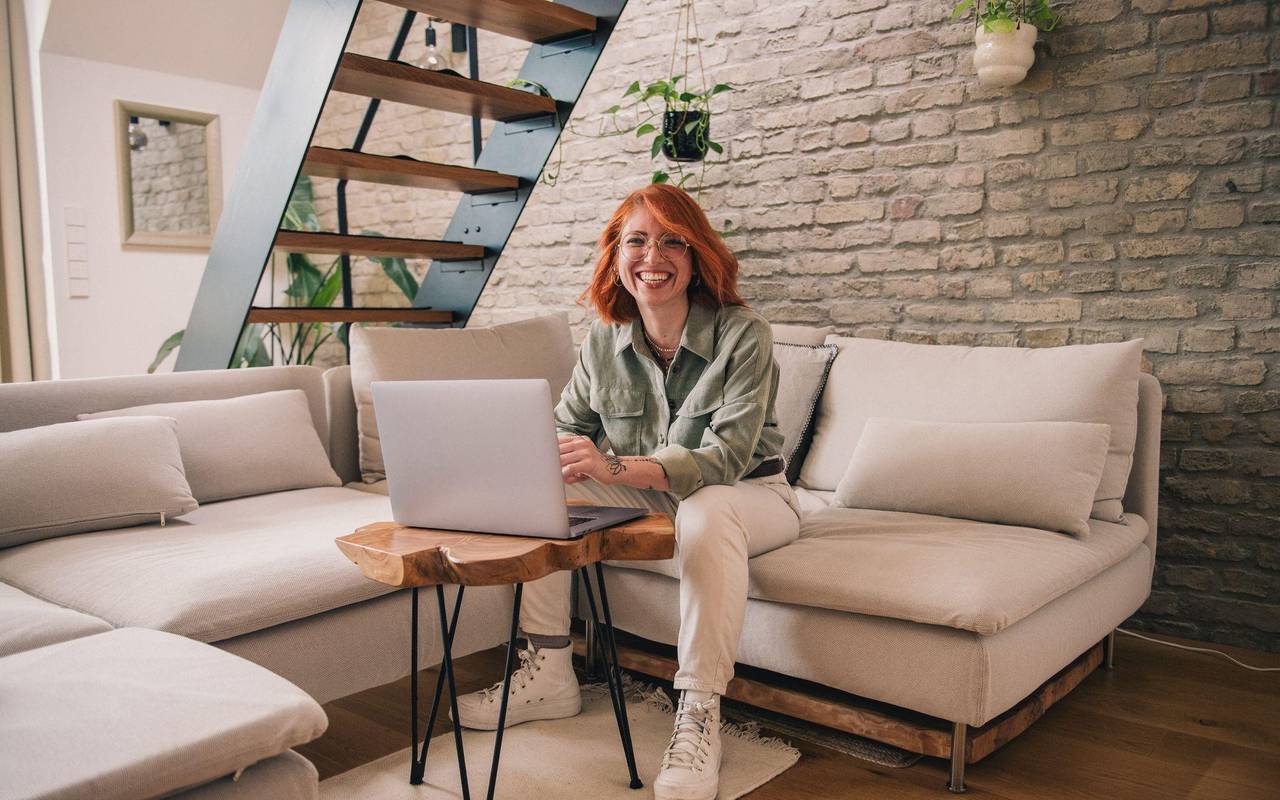 Eine Frau am Laptop sitzt auf einem Sofa