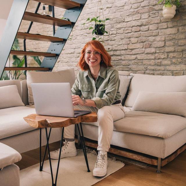 Eine Frau am Laptop sitzt auf einem Sofa