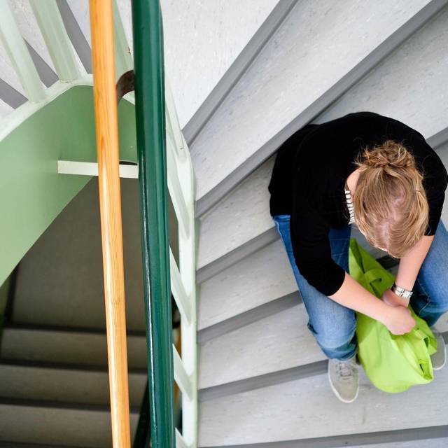 Eine Frau sitzt in einem Treppenhaus auf einer Treppenstufe