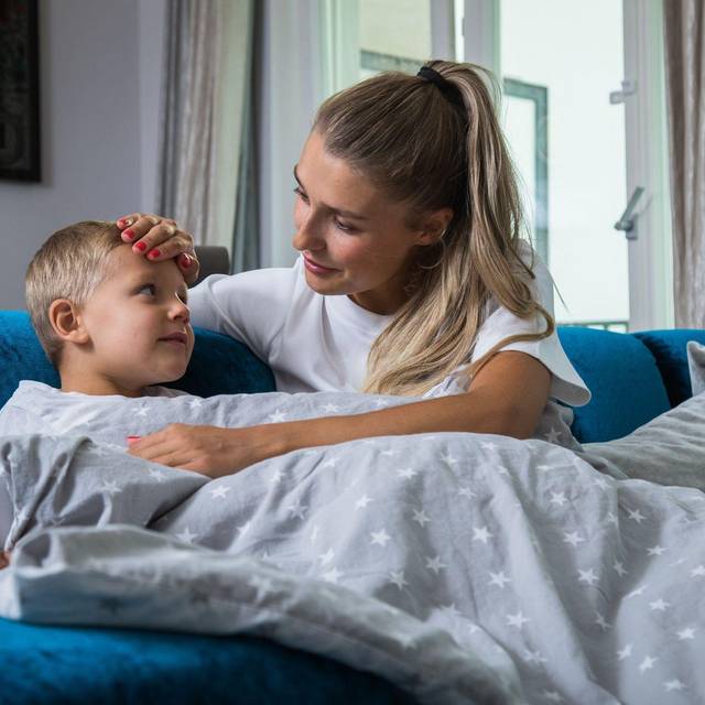 Eine Mutter legt ihre Hand auf die Stirn ihres Sohnes