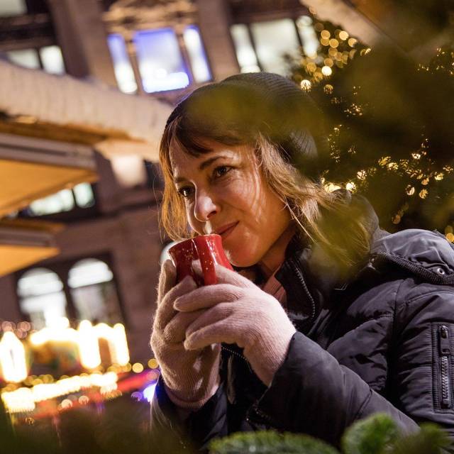 Frau trinkt auf dem Weihnachstmarkt ein Heissgetränk