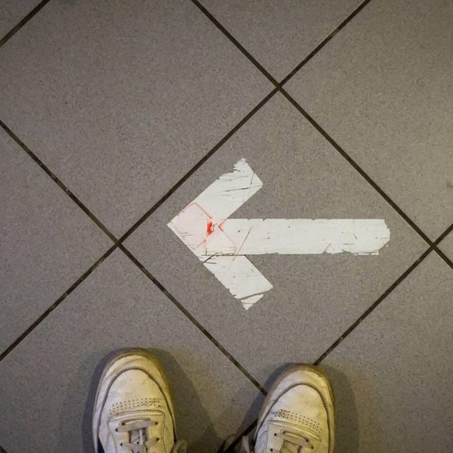Ein Pfeil aus Klebeband ist auf einem Fußboden zu sehen