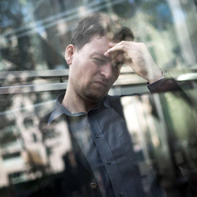 Mann hält sich mit der Hand seinen schmerzenden Kopf