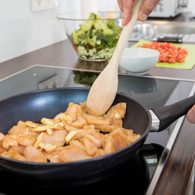 Ein Mann brät Hähnchenfleisch in einer Pfanne
