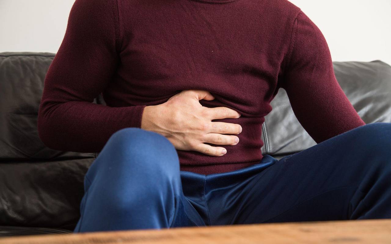 Ein Mann fasst sich mit der Hand an den Bauch