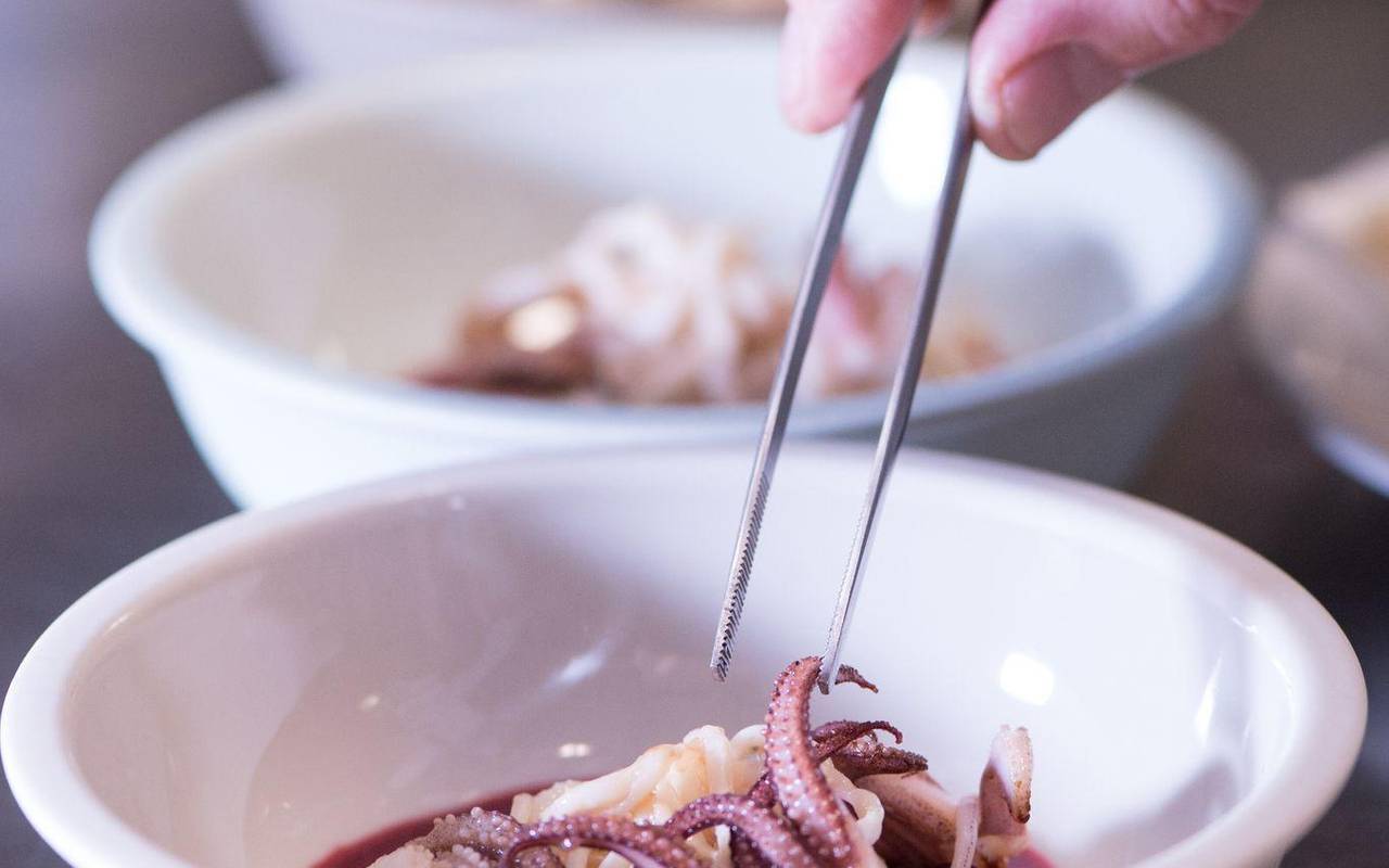 Koch richtet mit einer Pinzette ein Gericht an