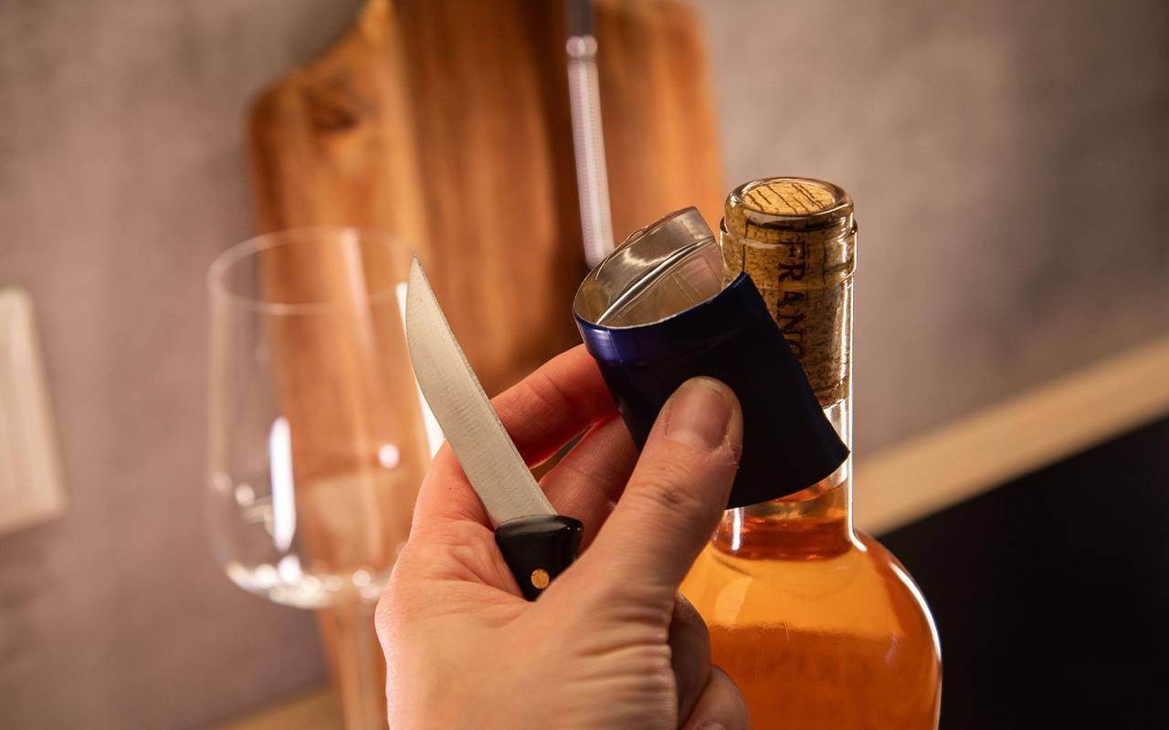 Banderole wird vom Flaschenhals eines Weins entfernt