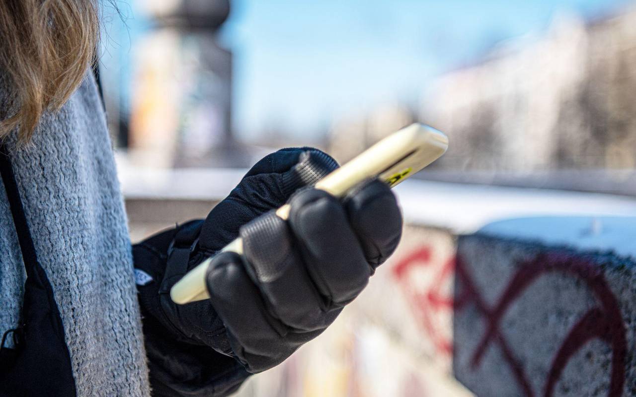 Eine warm angezogene Frau hält bei Kälte ein Handy