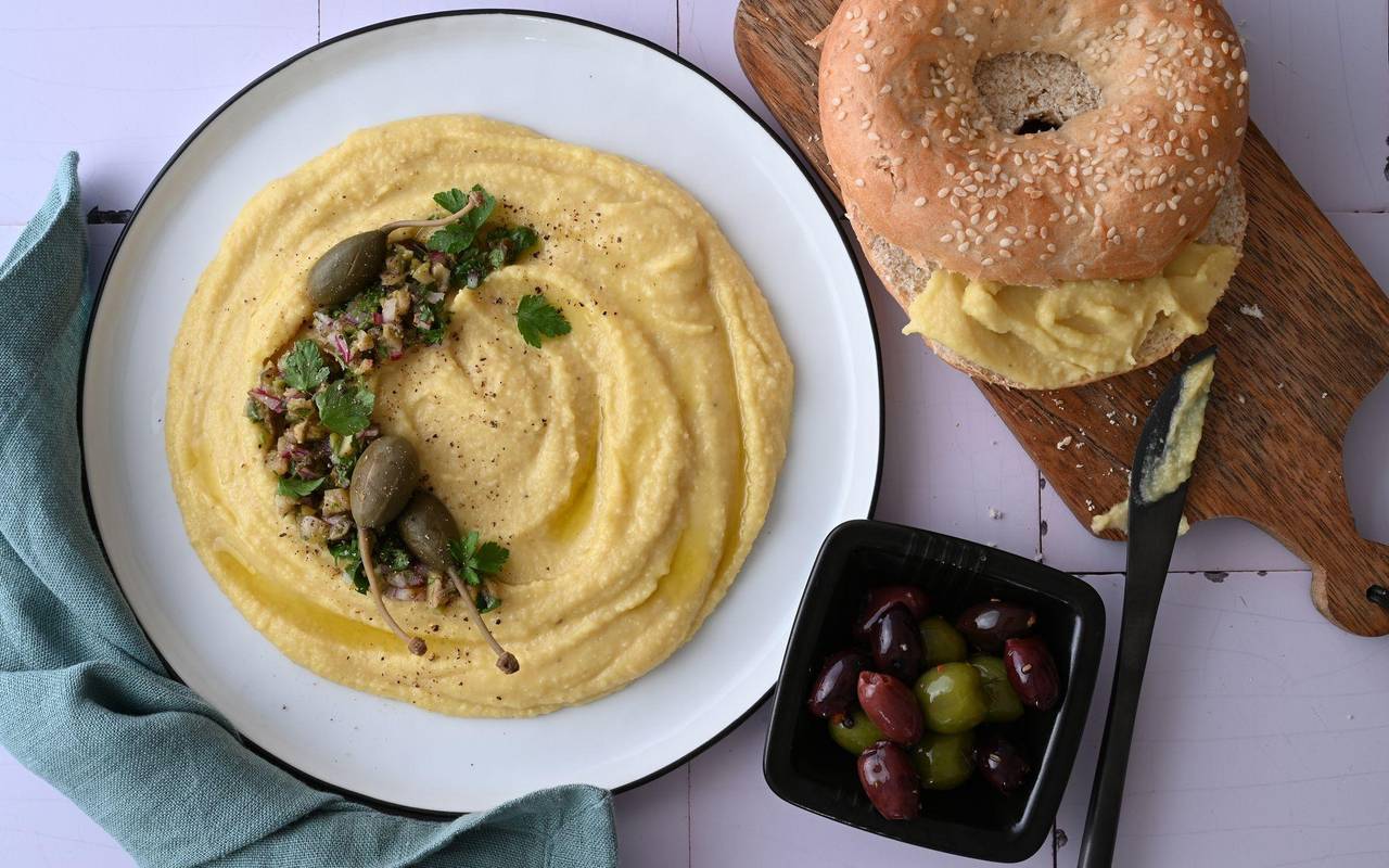 Ein Teller Linsendip, ein Bagel und eine Schale Oliven