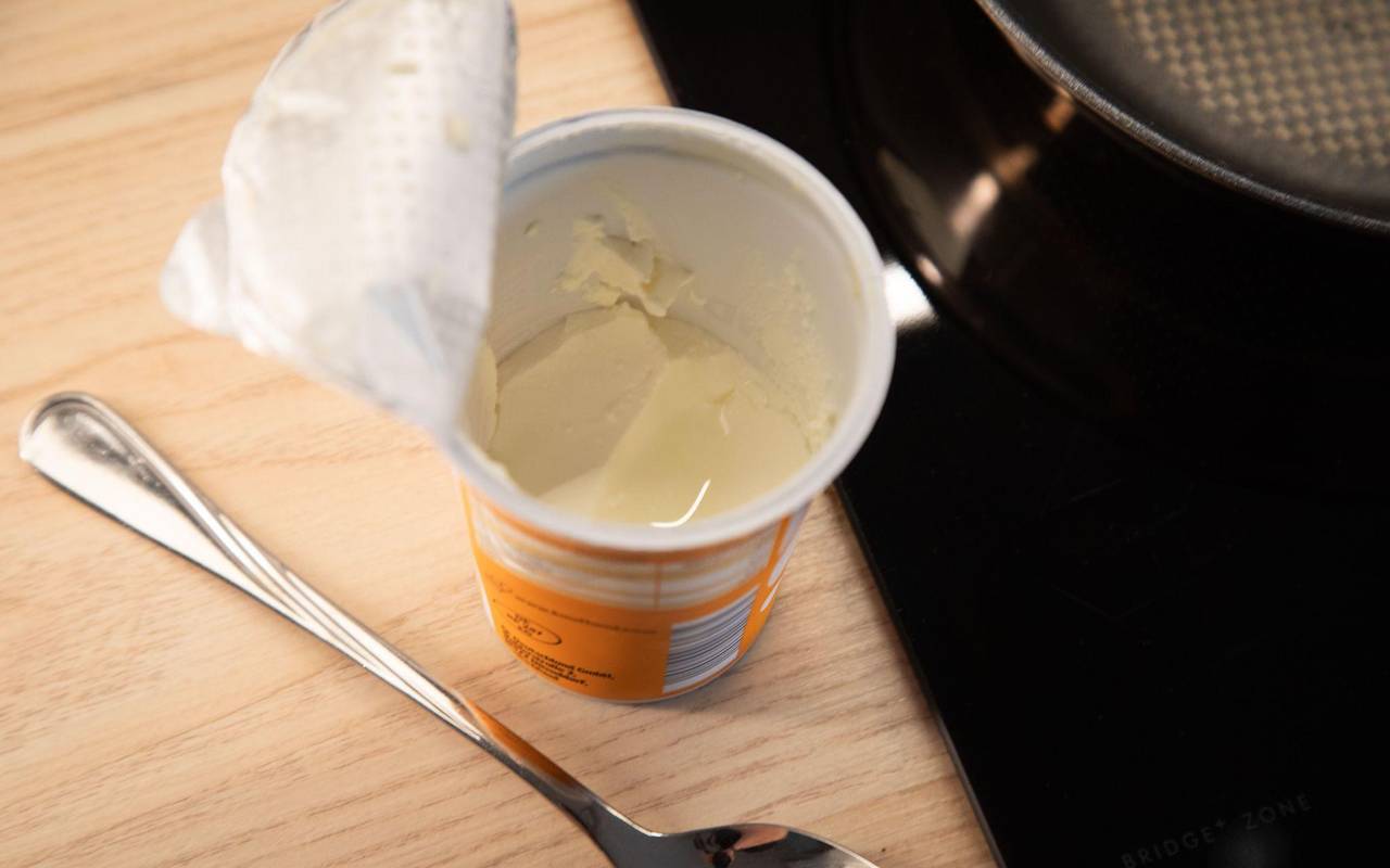 Geöffneter Becher Schmand steht in einer Küche