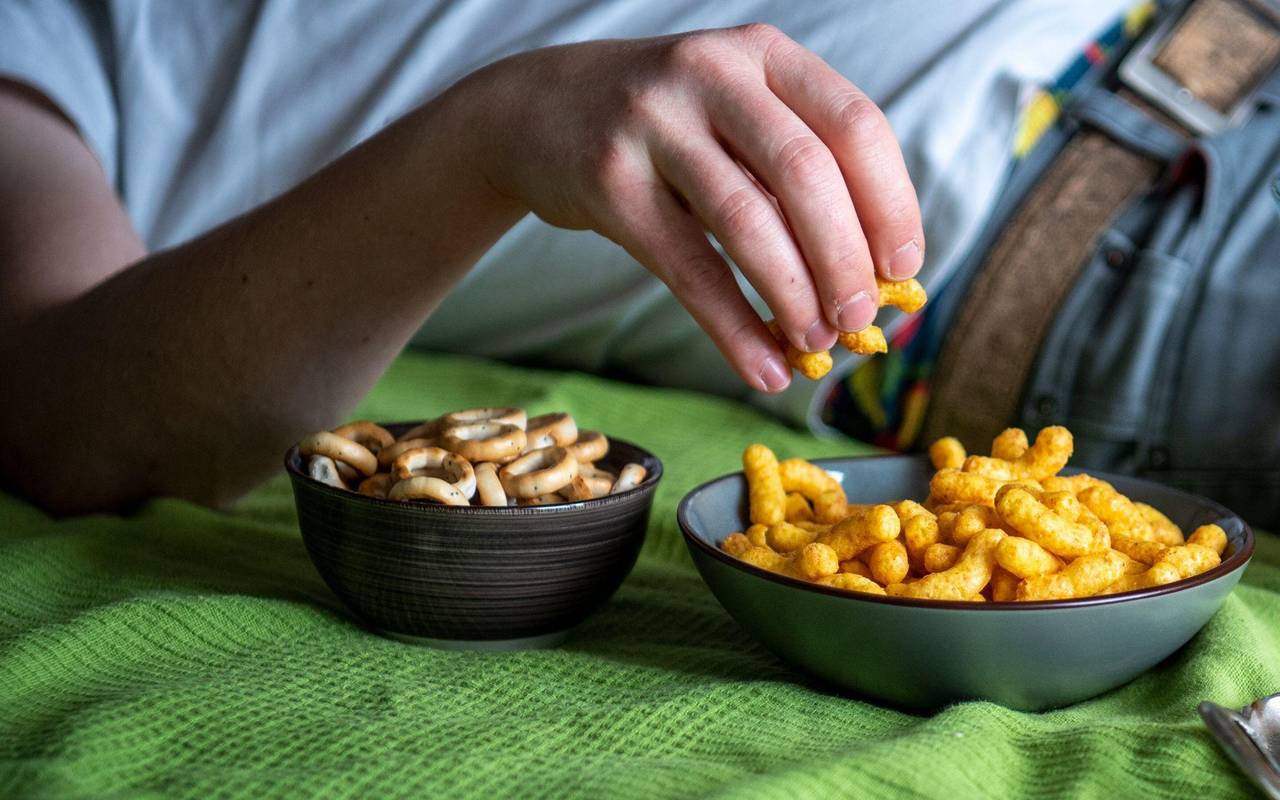 Mann isst auf einem Sofa Chips
