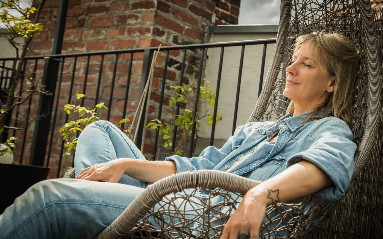 Frau sitzt entspannt im Hängesessel auf einer Terrasse