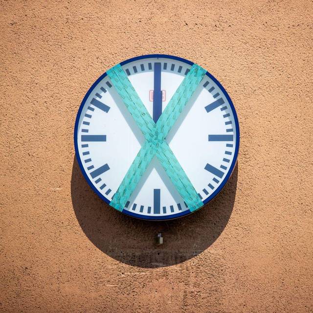 Eine abgeklebte Bahnhofsuhr hängt an einer Wand