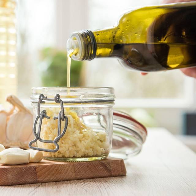 Olivenöl wird in ein Einmachglas geschüttet