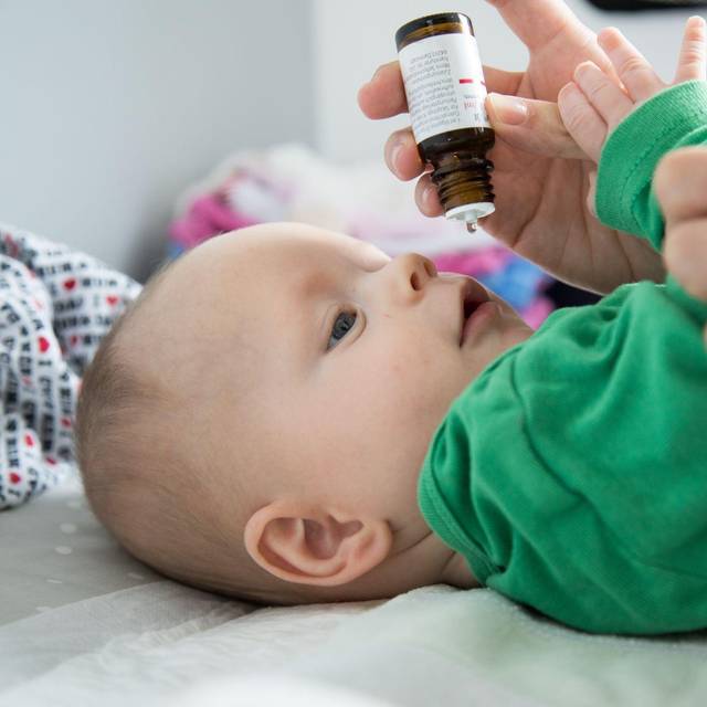 Eine Mutter verabreicht ihrem Baby Vitamin-D-Tropfen