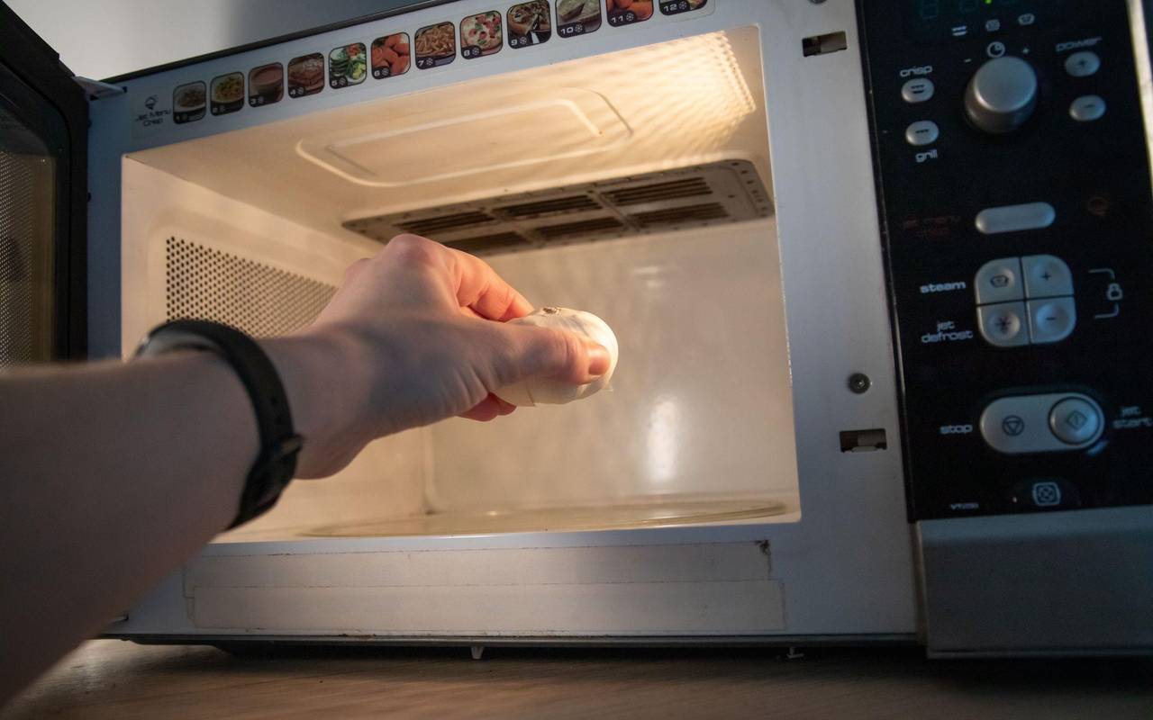 Eine Frau legt eine Knoblauchknolle in die Mikrowelle