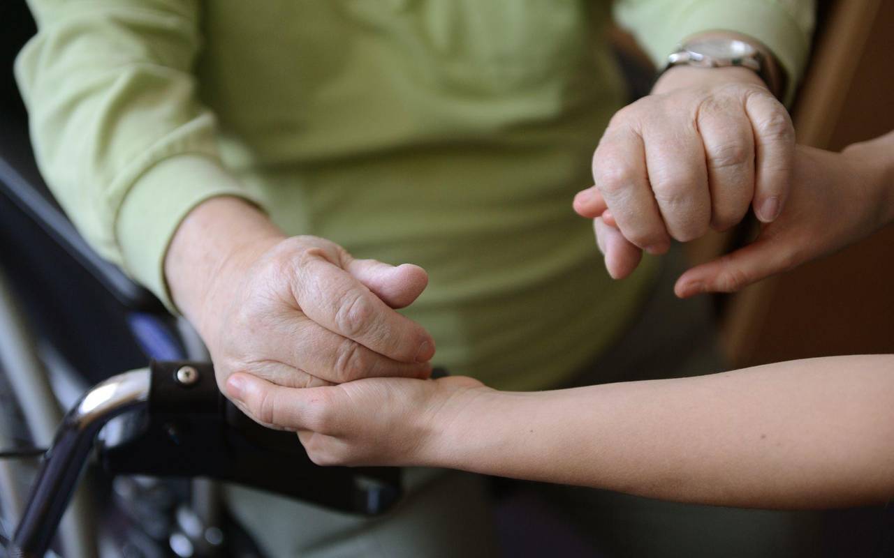 Eine junge Frau hält die Hände eines alten Mannes