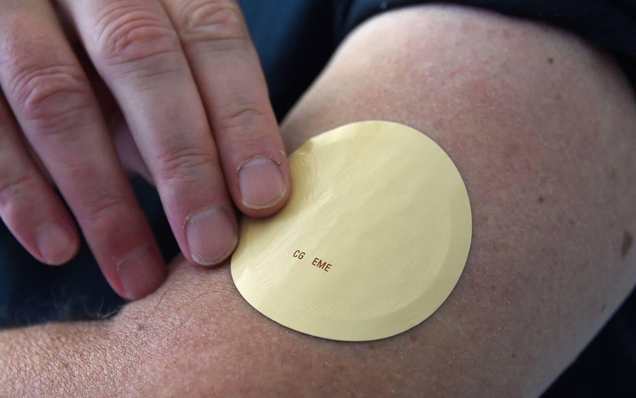 Eine Person trägt ein Wirkstoffpflaster am Oberarm