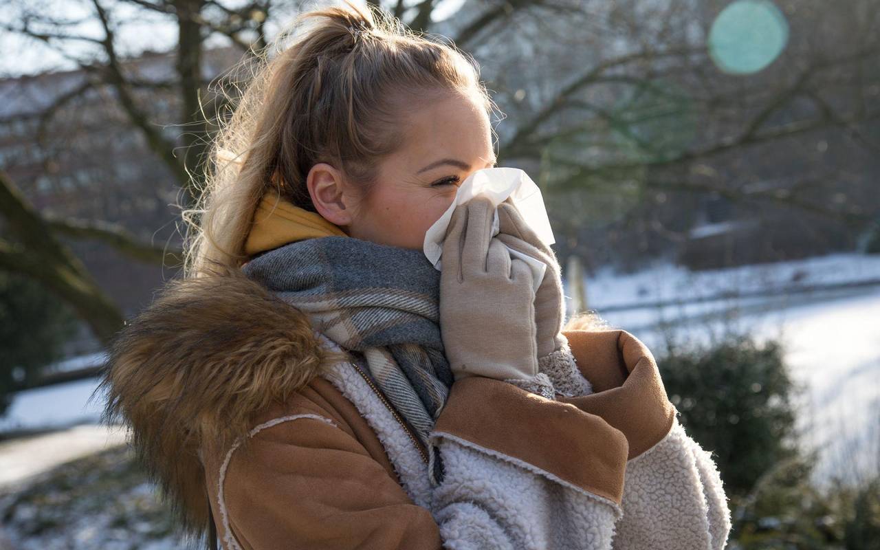 Frau putzt sich im Park die Nase
