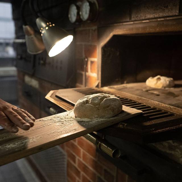 Teig wird auf einem Brotschieber in einen Ofen geschoben