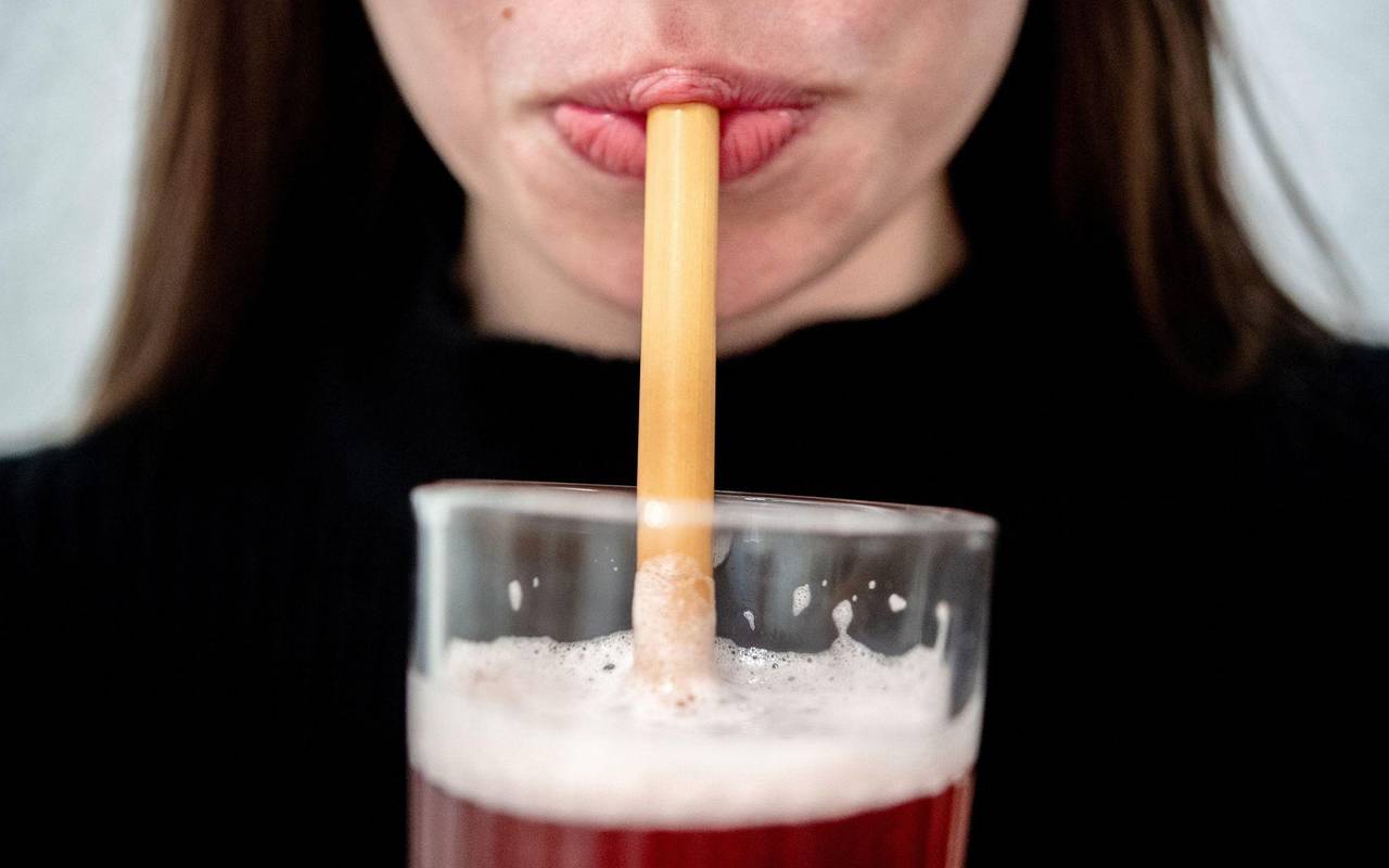 Eine junge Frau trinkt durch einen Trinkhalm aus Bambus