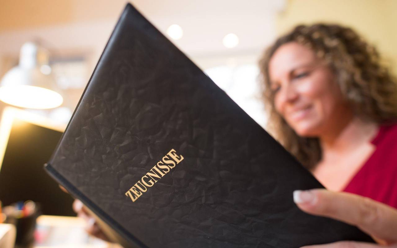 Frau liest in einer Mappe mit der Aufschrift «Zeugnisse»