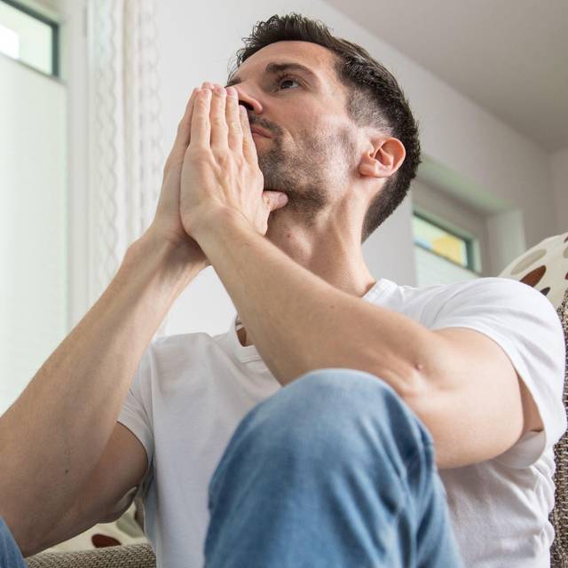Mann sitzt nachdenklich im Wohnzimmer