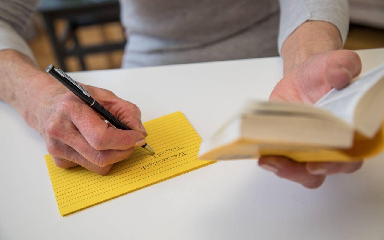 Eine Frau notiert Vokabeln aus einem Woerterbuch heraus