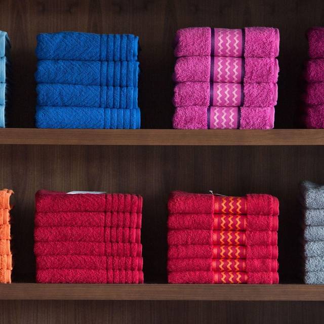 Nach Farben sortierte Handtücher in einem Regal
