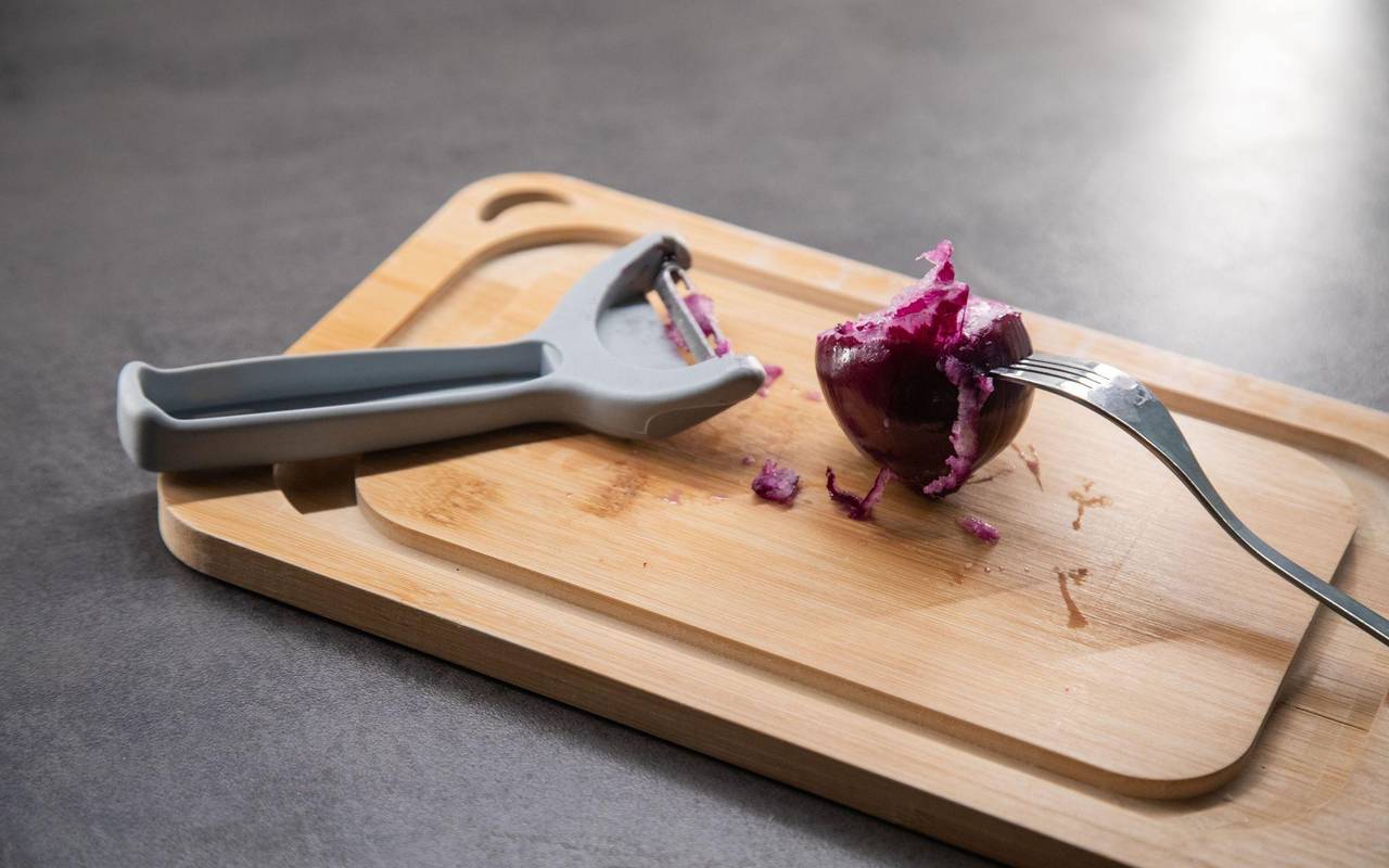 Sparschäler liegt neben einer Zwiebel