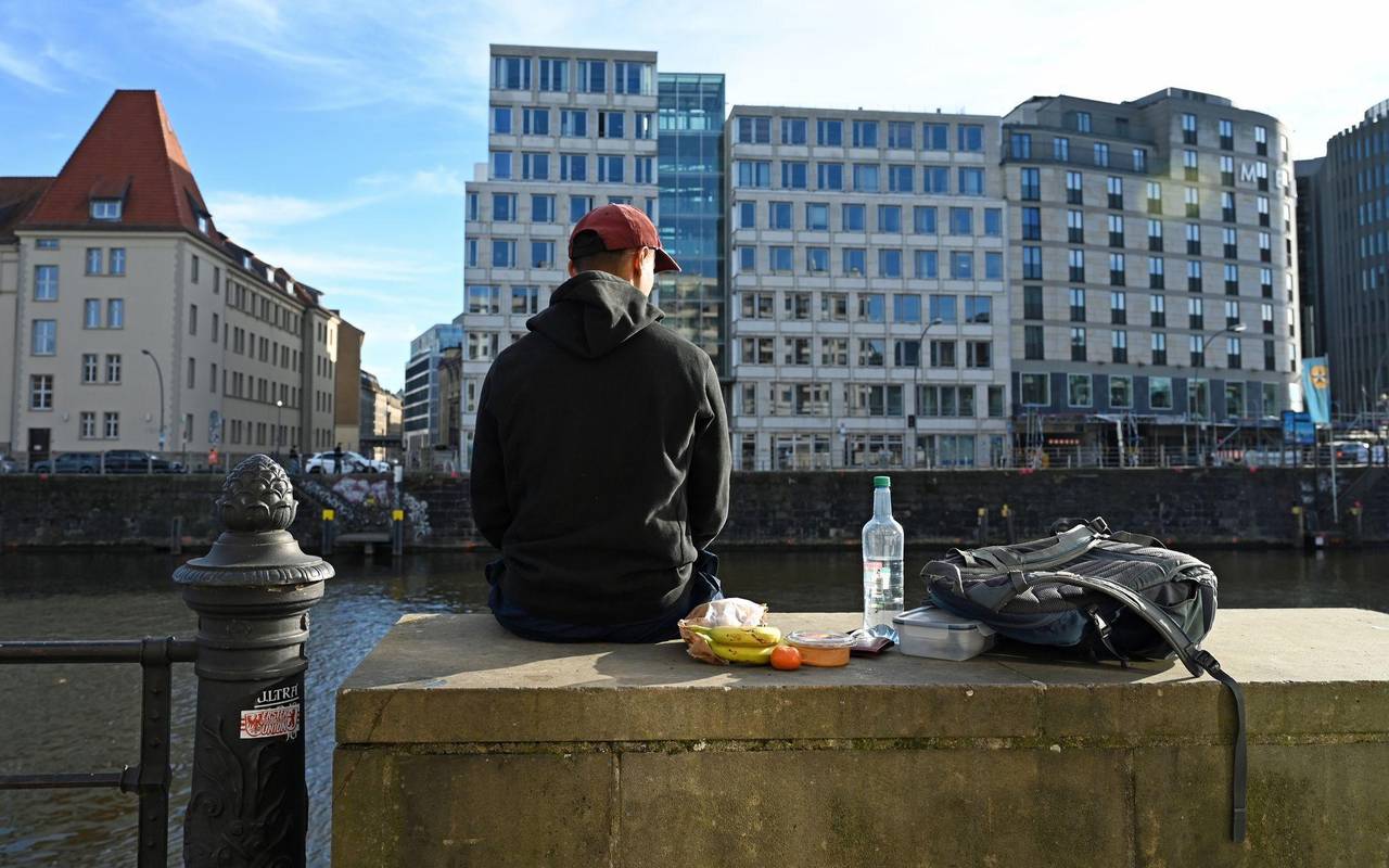 Ein Mann sitzt in der Sonne auf einer Mauer an der Spree