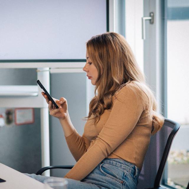Junge Frau mit Smartphone im Büro