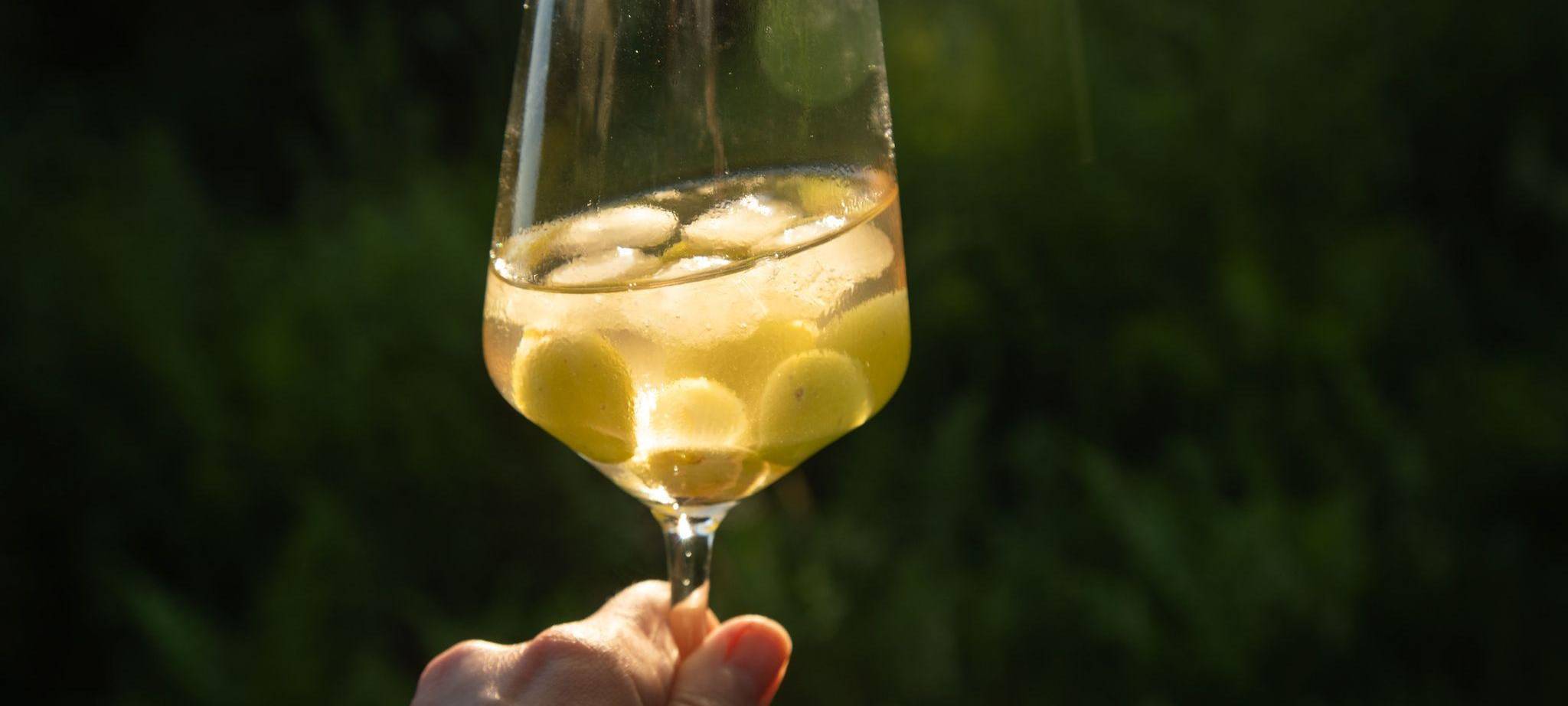 Eiswürfel aus Trauben und gefrorenem Wein kühlen einen Weißwein