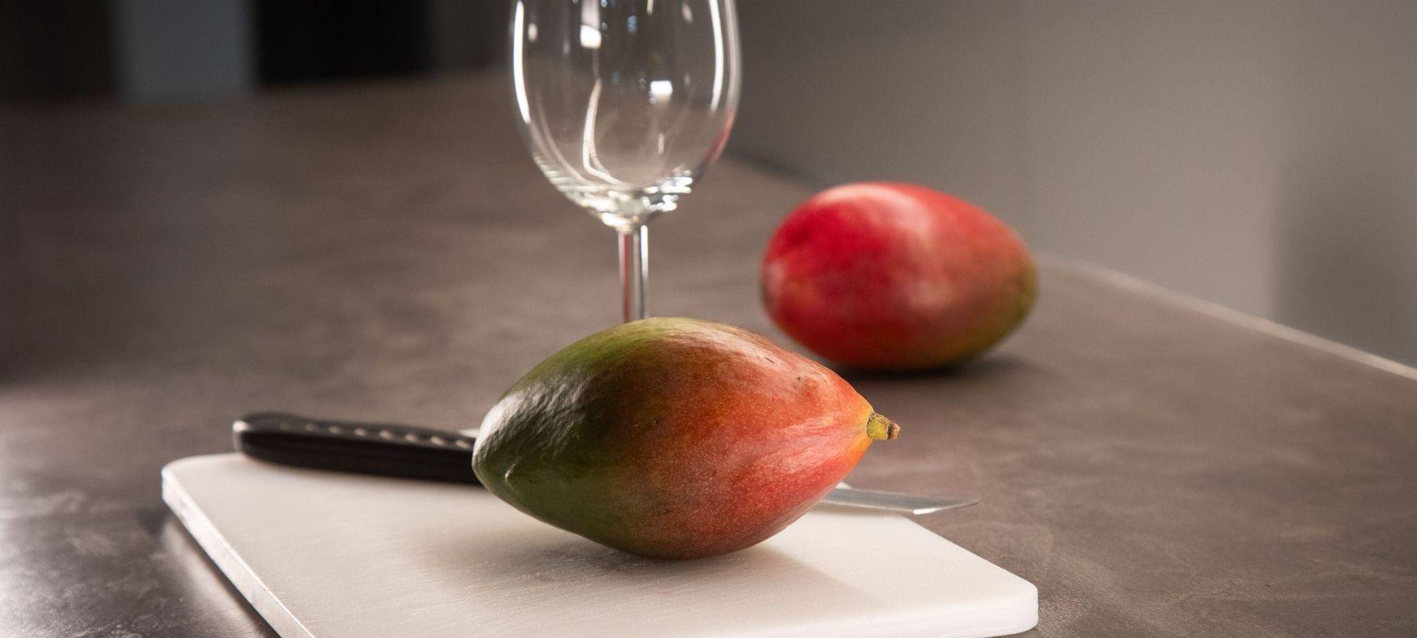 Mango liegt neben einem Weinglas auf einem Schneidebrett