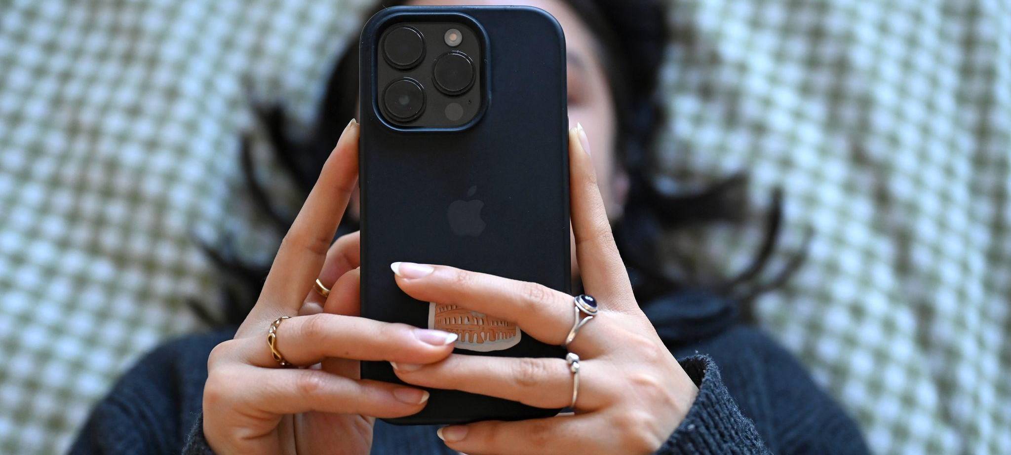 Eine junge Frau liegt mit dem Smartphone in der Hand auf dem Bett