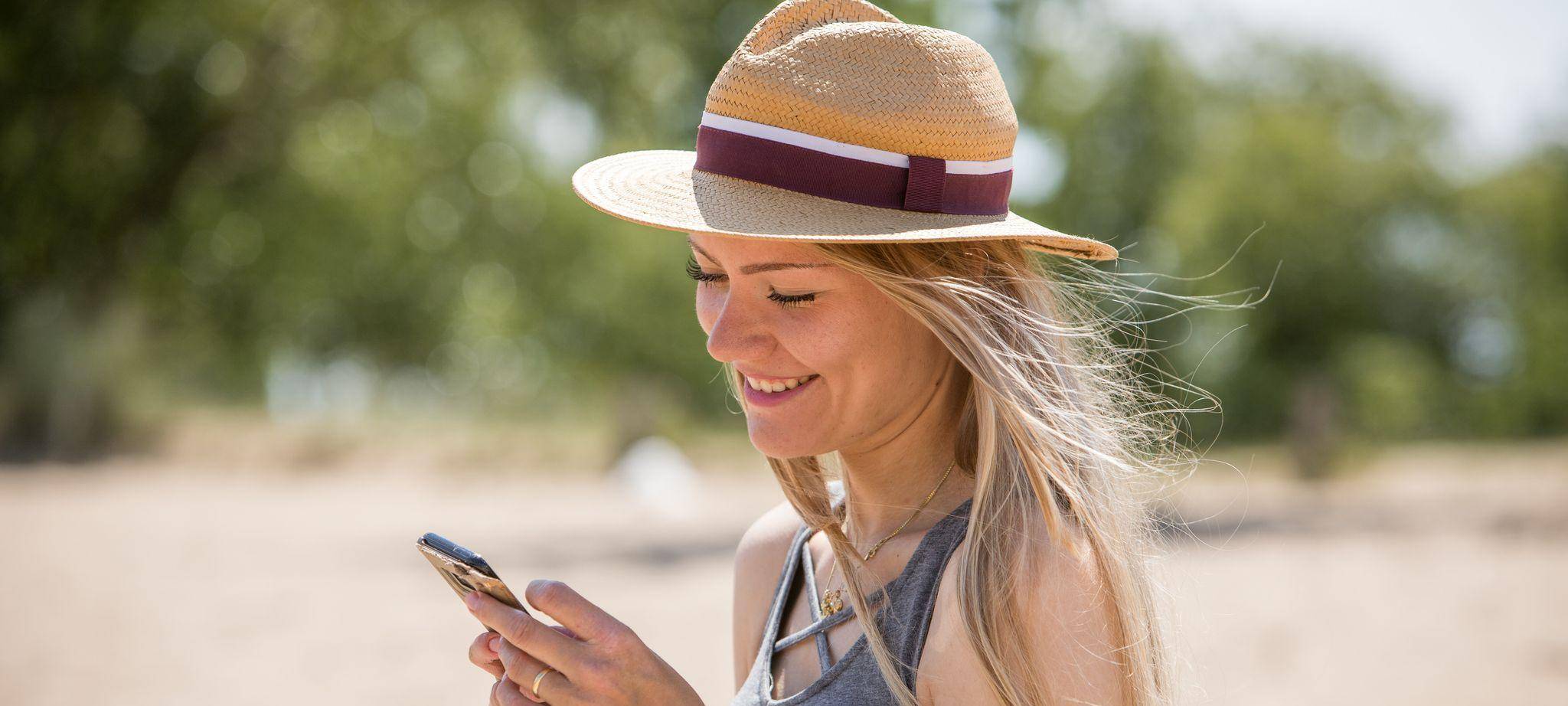 Eine junge Frau nutzt ihr Handy am Strand