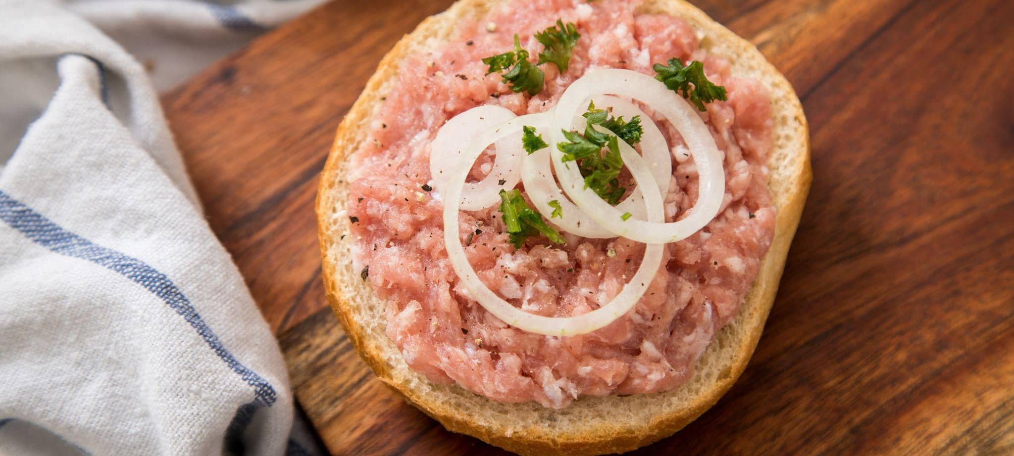 Mettbrötchen liegt auf einem Holzbrett